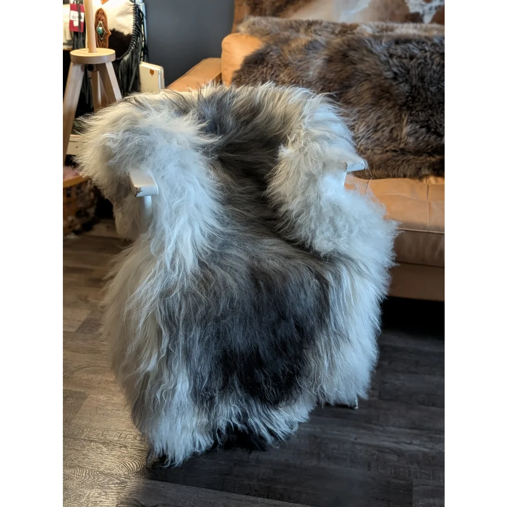 A plush 58 by 37 inch long wool icelandic sheepskin throw in natural grey and white blend for cozy decor