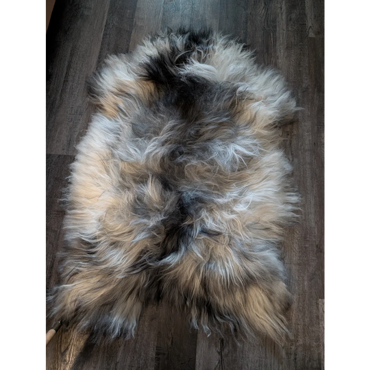 A plush naturally colored icelandic sheepskin rug with cream gray and black long wool icelandic fur measuring 58 x 37 inches
