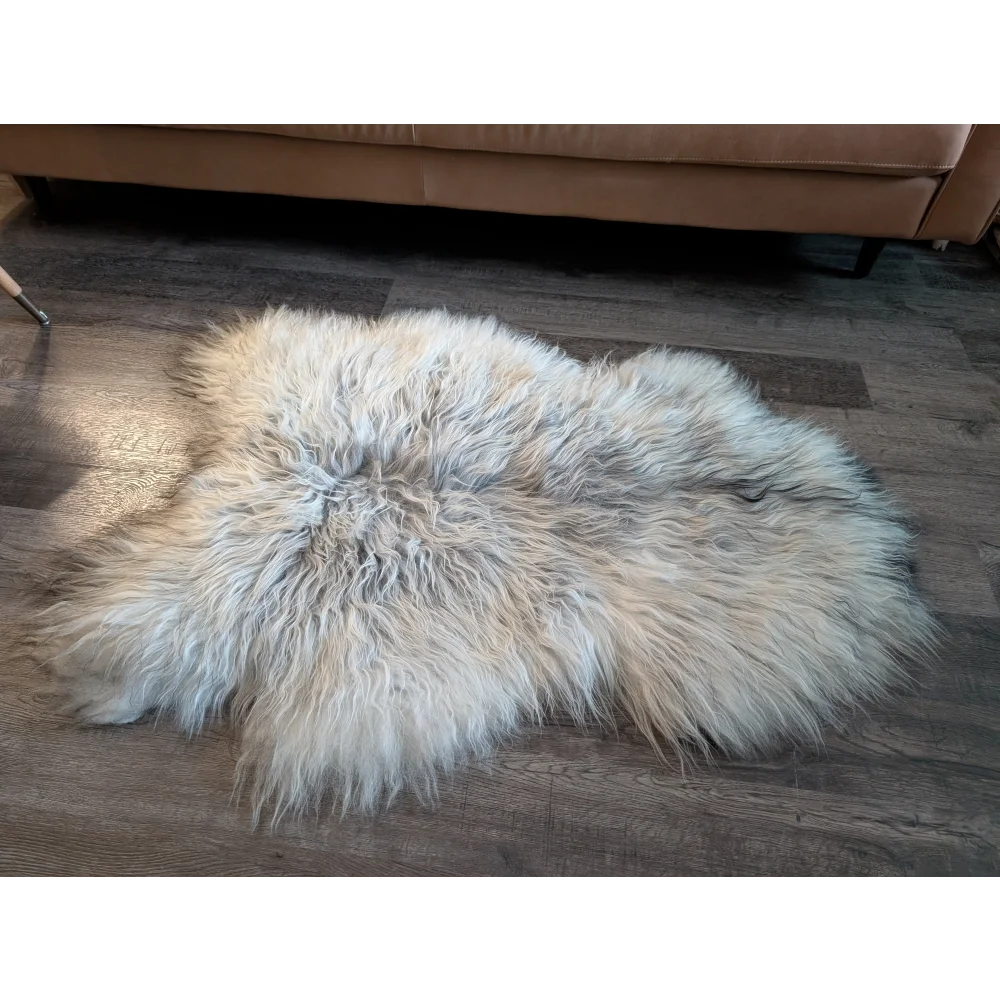 A fluffy cream icelandic sheepskin rug with long wool icelandic fibers in a natural irregular shape 55 x 35 inches