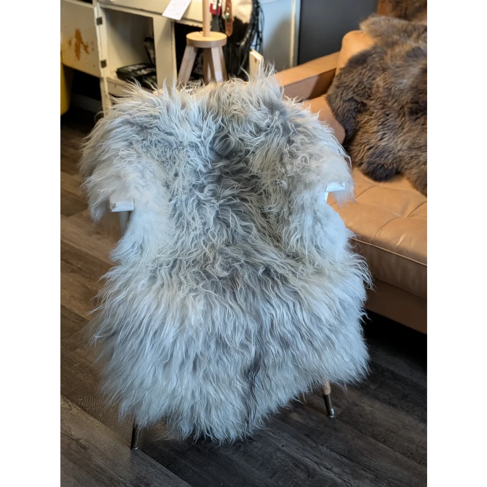 A plush light gray icelandic sheepskin chair cover with long wool icelandic fur on a modern metal-framed chair