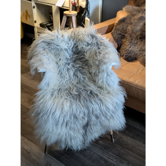 A plush light gray icelandic sheepskin chair cover with long wool icelandic fur on a modern metal-framed chair