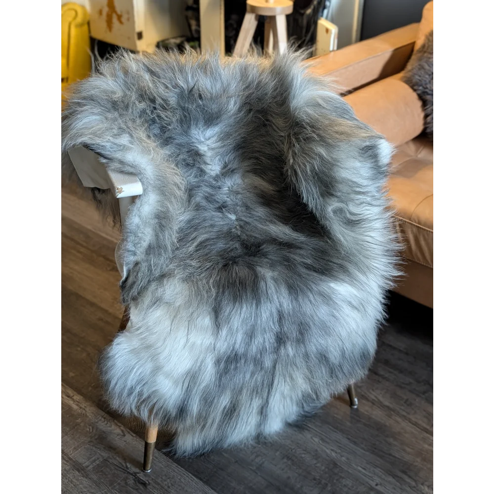A plush icelandic sheepskin rug in natural grey with long wool icelandic fur draped over a modern chair