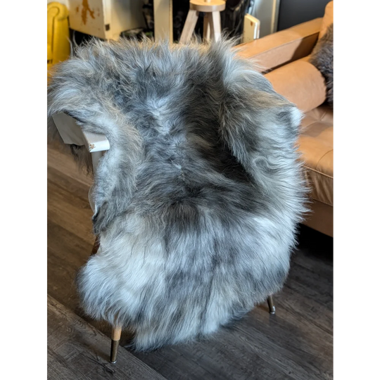 A plush icelandic sheepskin rug in natural grey with long wool icelandic fur draped over a modern chair