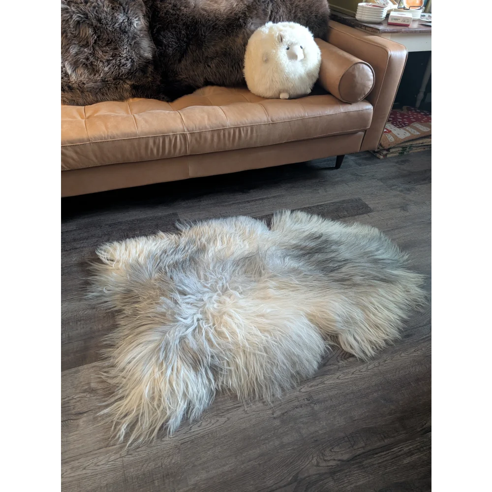A fluffy cream-colored icelandic sheepskin rug with long soft fibers on a wooden floor for cozy decor