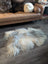 A fluffy cream-colored icelandic sheepskin rug with long soft fibers on a wooden floor for cozy decor