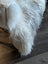 A plush long-haired white wool icelandic faux fur throw draped over furniture edge for cozy style