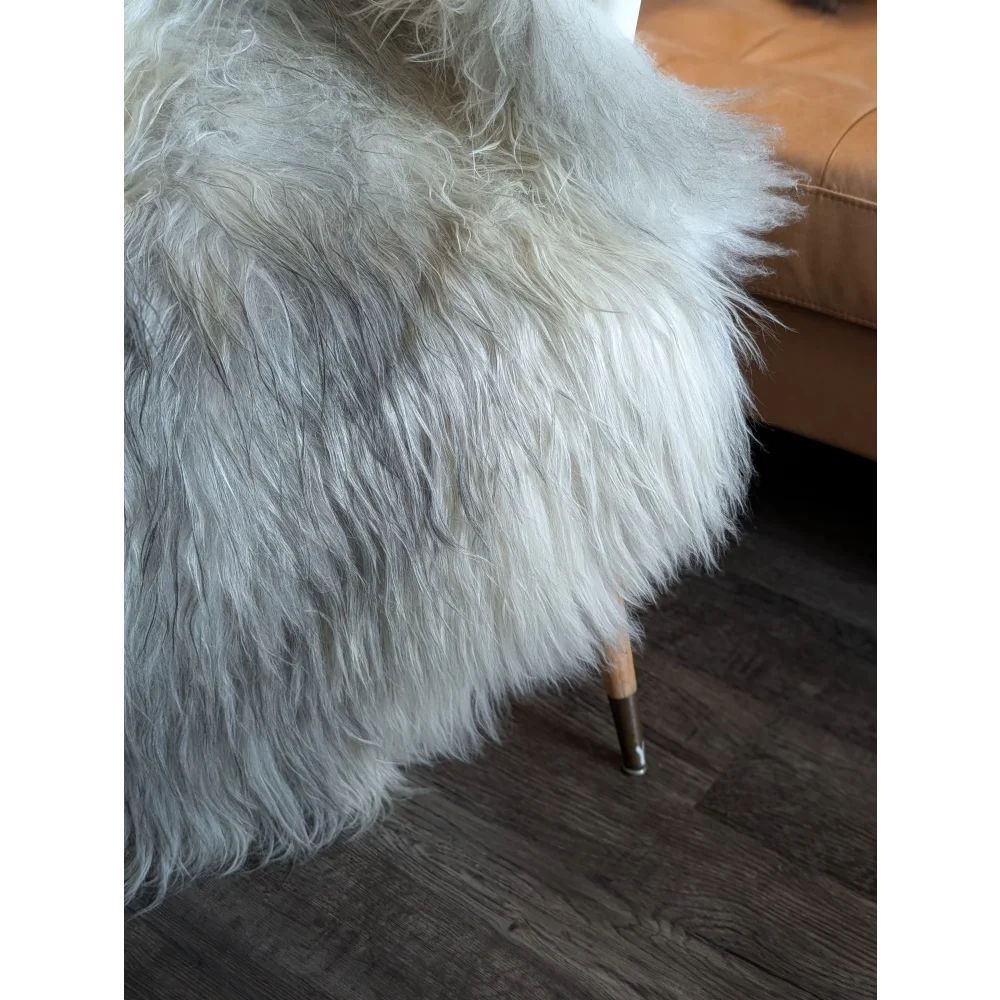 A plush white double icelandic wool faux fur throw draped over a chair leg for cozy home decor