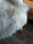A plush white double icelandic wool faux fur throw draped over a chair leg for cozy home decor