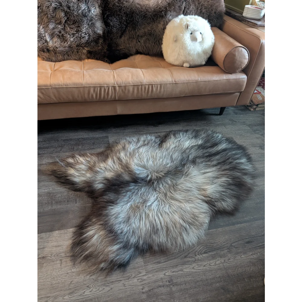 A plush 54 x 34 inch massive icelandic sheepskin rug in natural grey with double icelandic wool on wooden floor