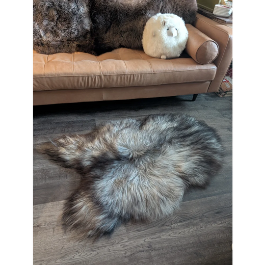 A plush 54 x 34 inch massive icelandic sheepskin rug in natural grey with double icelandic wool on wooden floor
