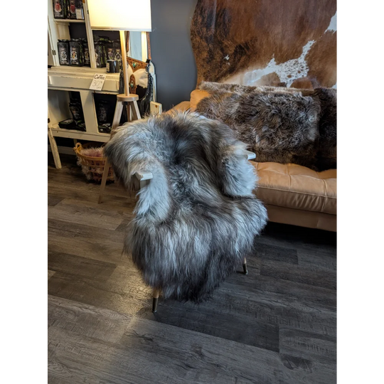 A massive 54 x 34 inch double icelandic sheepskin throw in natural grey draped over a modern chair with gold legs