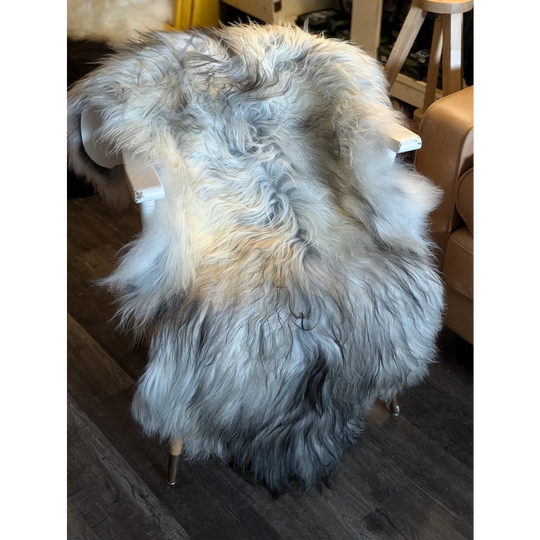 A plush long-haired icelandic sheepskin rug in natural grey draped over a modern chair with wool icelandic texture