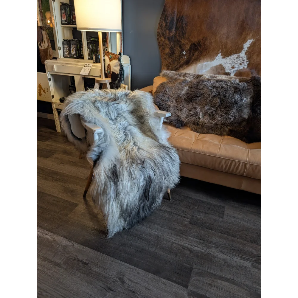 A plush wool icelandic sheepskin throw in natural grey draped over a wooden chair, measuring 58 by 32 inches