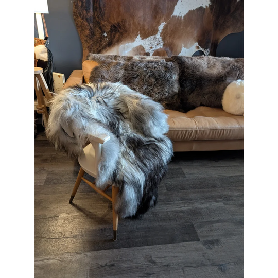 A plush double icelandic sheepskin throw in natural grey wool icelandic draped over a light wood chair