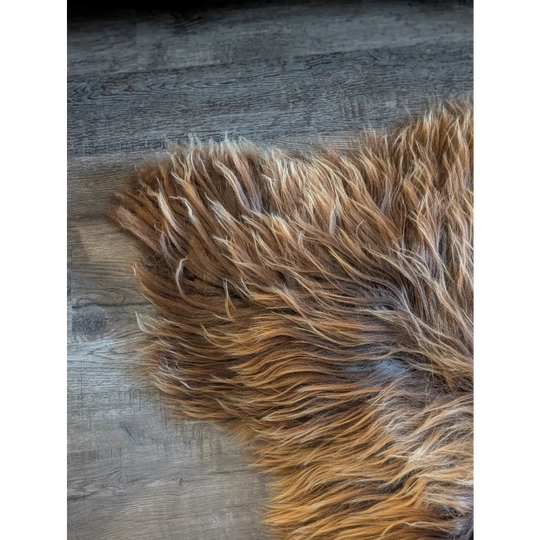 A massive icelandic sheepskin rug with long wool icelandic fibers in natural bronze on a dark wood floor