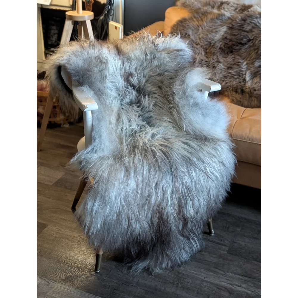 A plush long-haired grey wool icelandic sheepskin rug draped over a white wooden chair for cozy decor