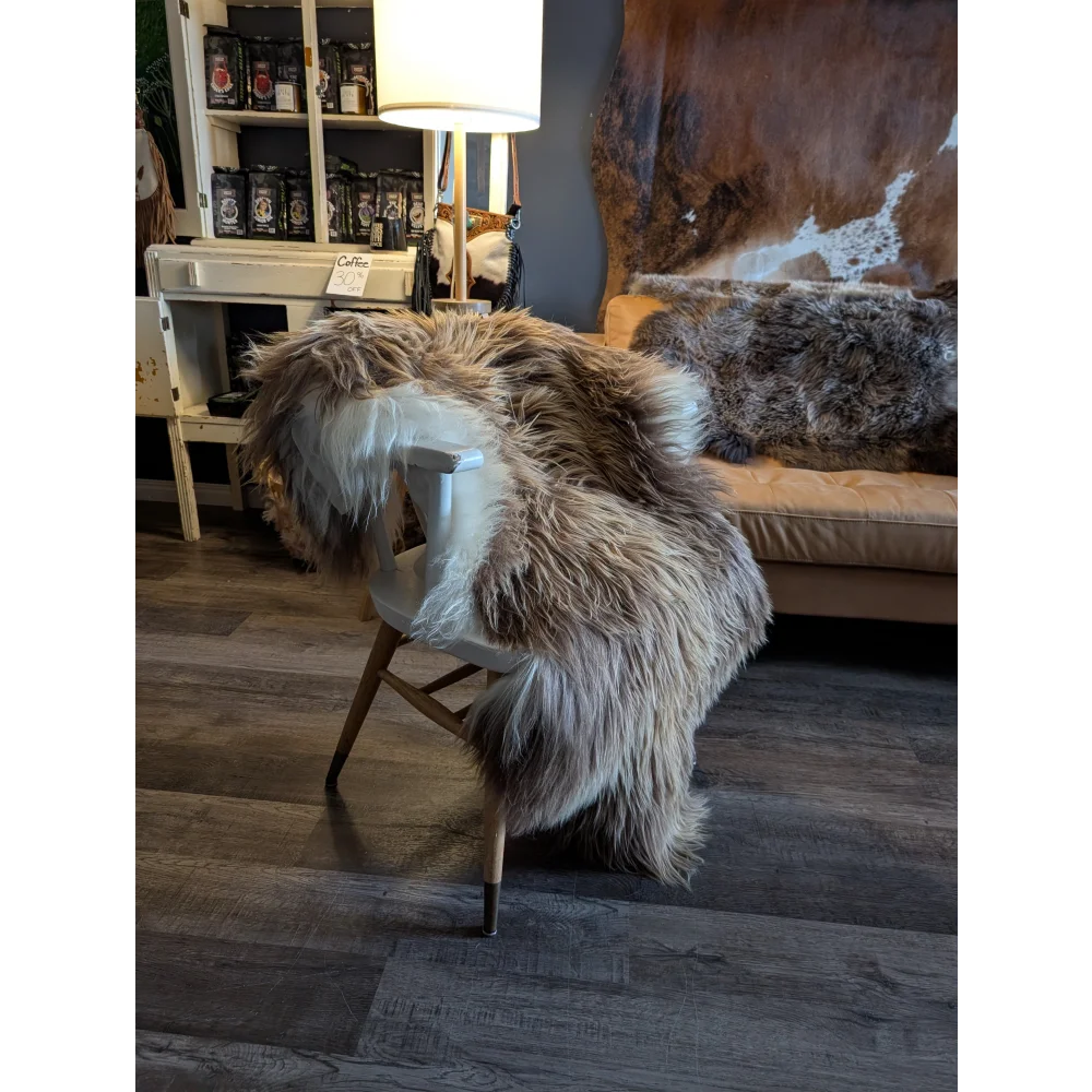 A plush long wool icelandic sheepskin throw in natural bronze and white draped over a modern wooden chair