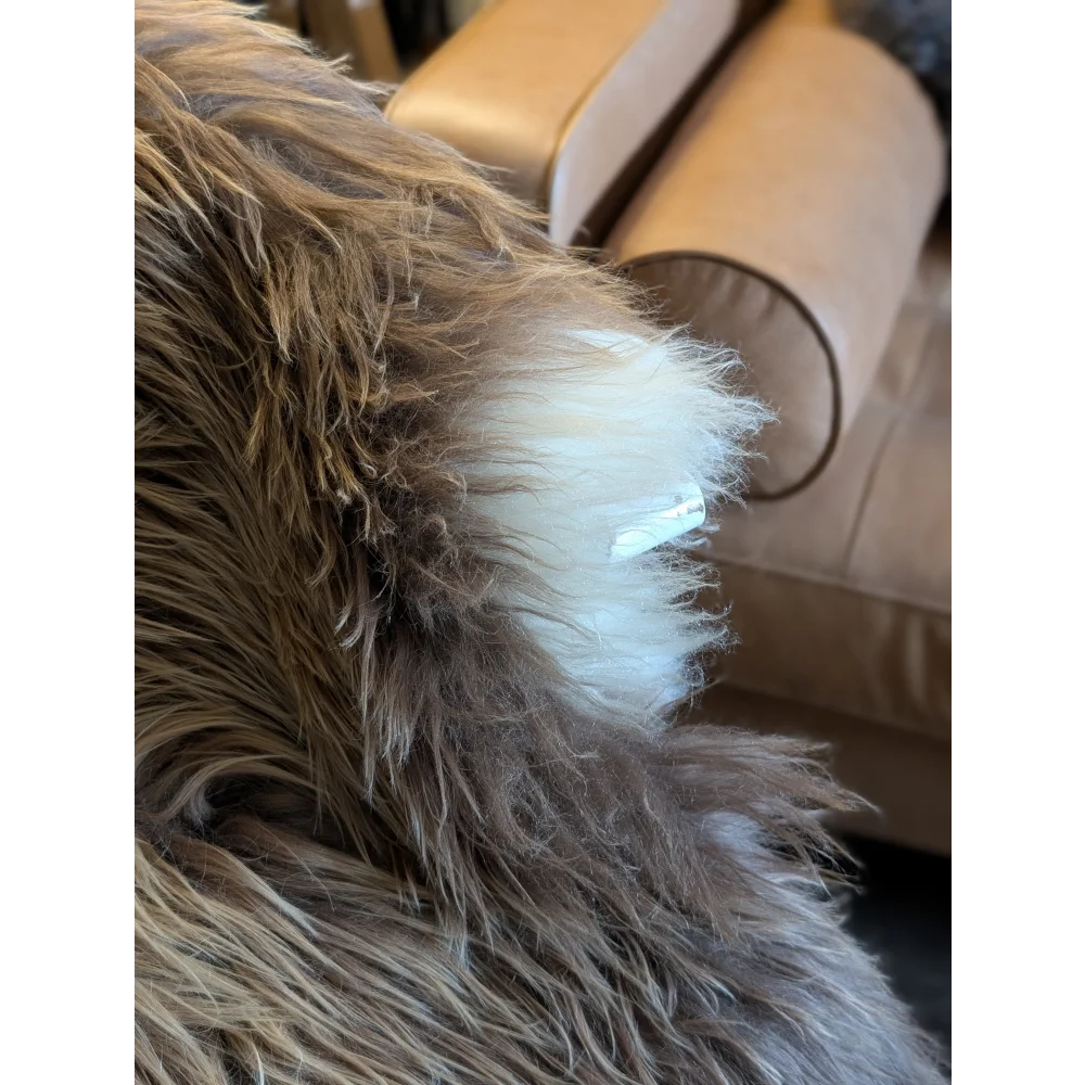 A white fluffy wool icelandic fur patch with a small bronze clip on the natural long wool icelandic sheepskin