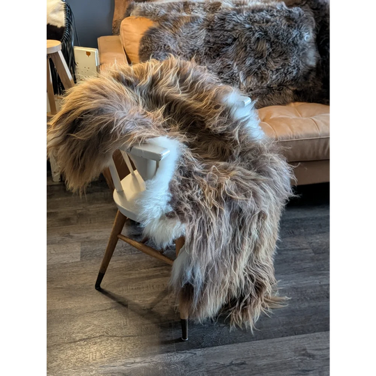 A long wool icelandic sheepskin throw in natural bronze draped over a wooden chair for cozy decor