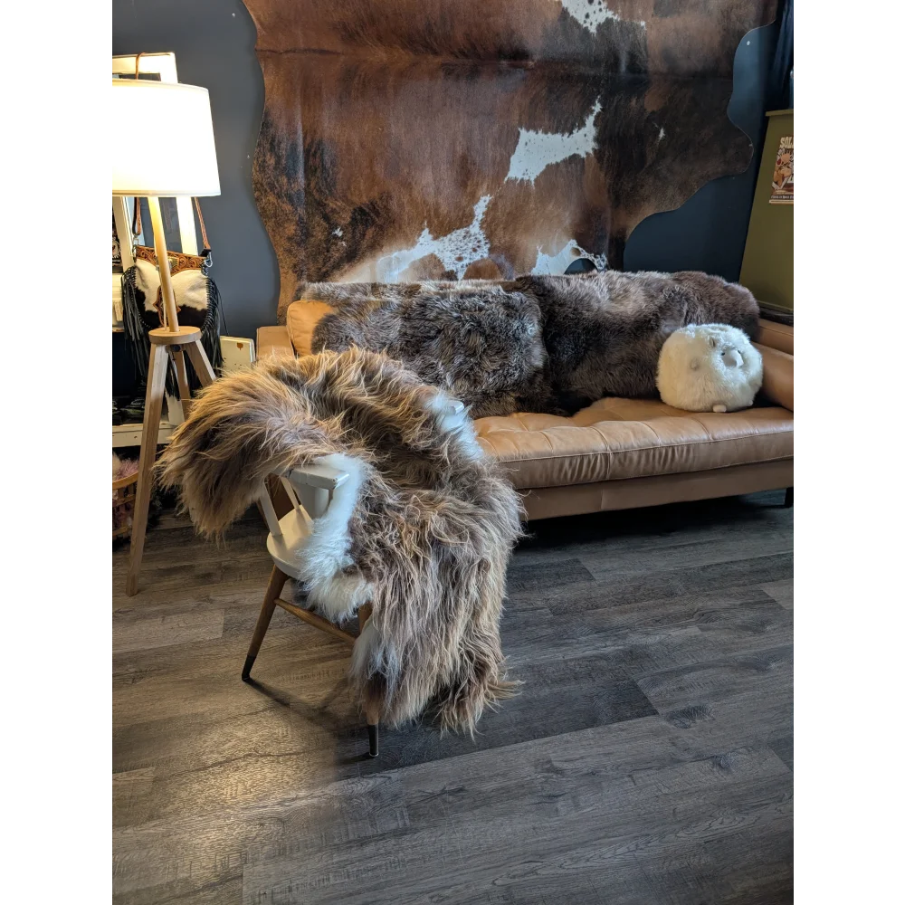 Tan leather sofa draped with thick shaggy brown and white long wool icelandic sheepskin throws natural bronze color
