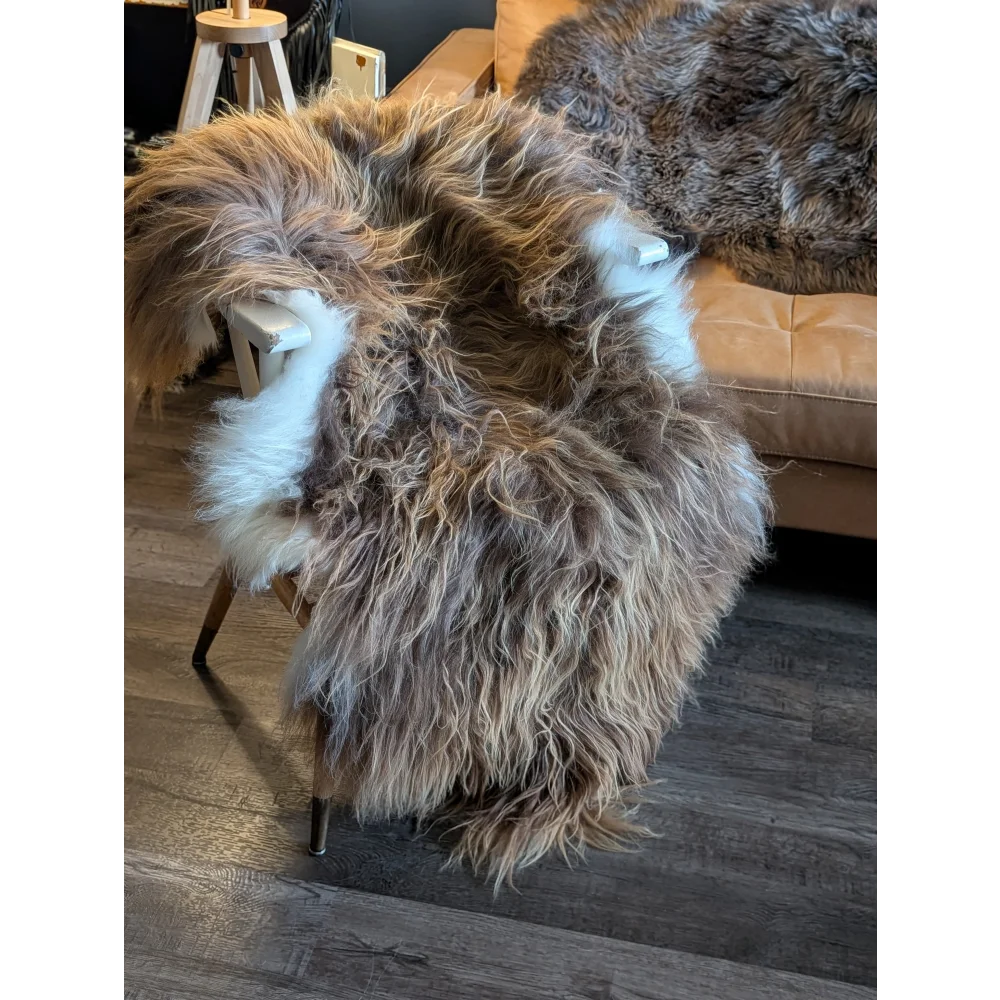 A plush long wool icelandic sheepskin rug in natural bronze tones draped over a wooden chair