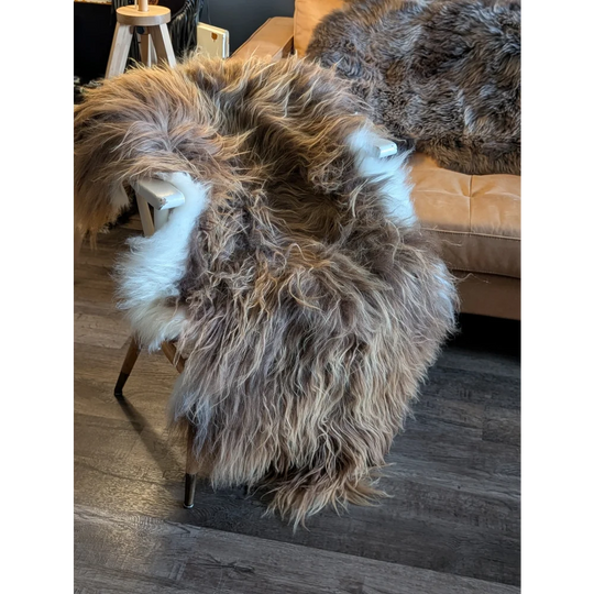 A plush long wool icelandic sheepskin rug in natural bronze tones draped over a wooden chair