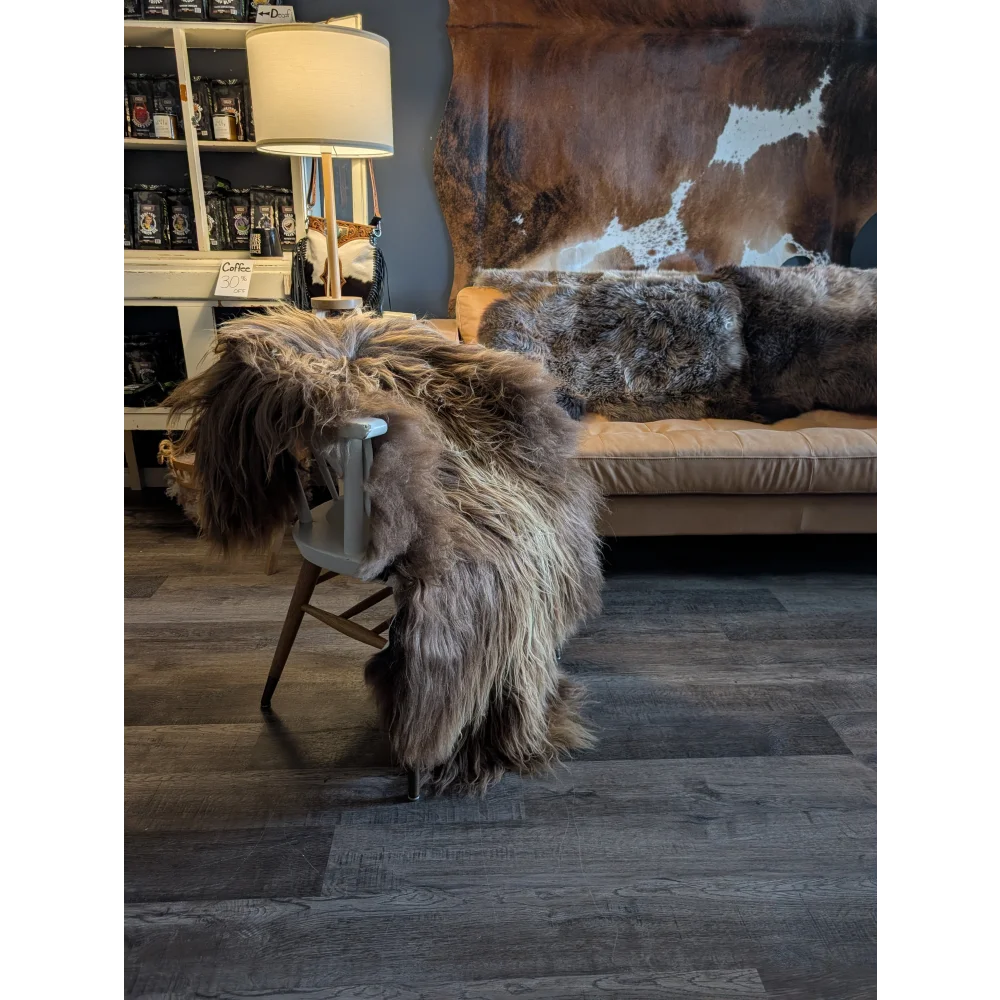 A thick shaggy brown and gray icelandic sheepskin rug draped over a white wooden chair showing natural bronze wool icelandic texture
