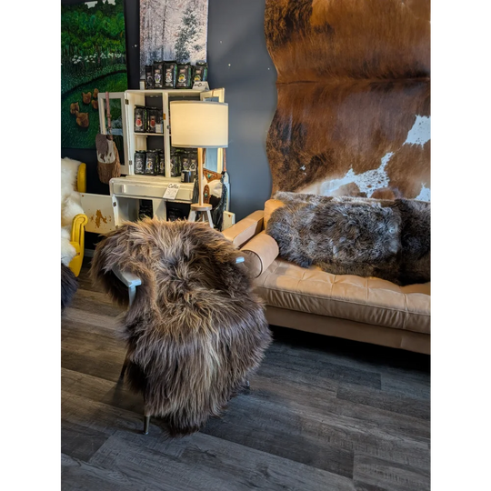 Thick shaggy wool icelandic sheepskin throw in natural bronze draped over a white chair for cozy decor