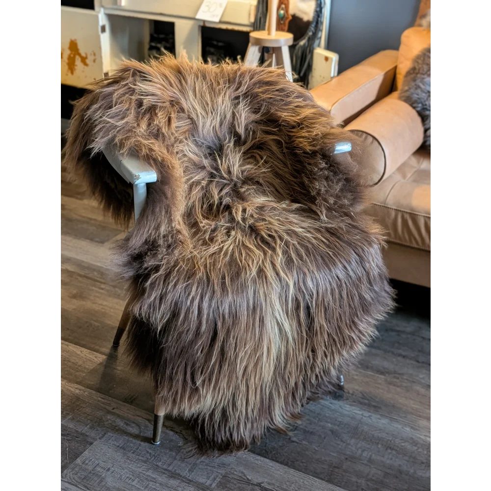 A plush long wool icelandic sheepskin rug in natural bronze draped over a modern chair for cozy style
