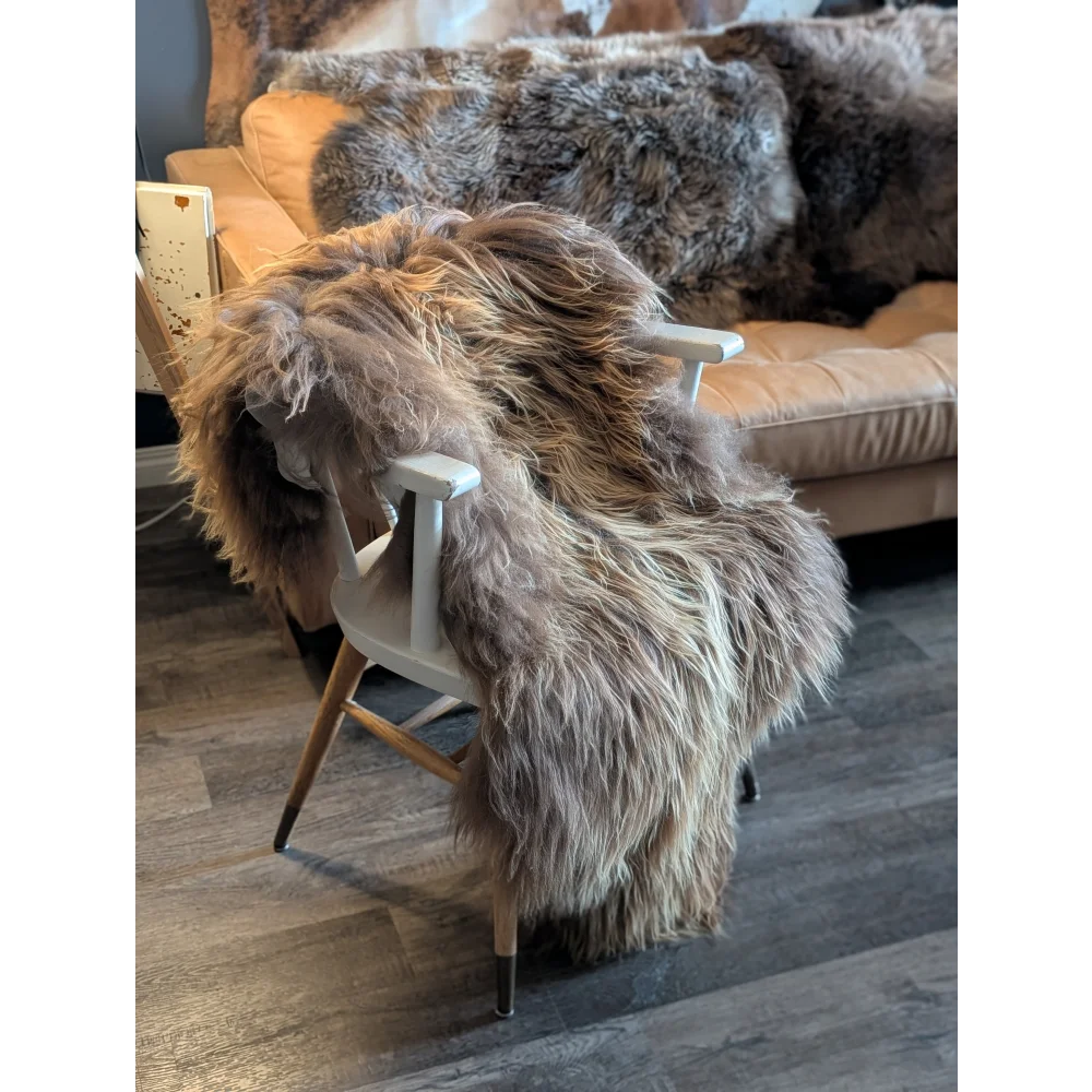 Thick shaggy long wool icelandic sheepskin rug in natural bronze draped over a white wooden chair