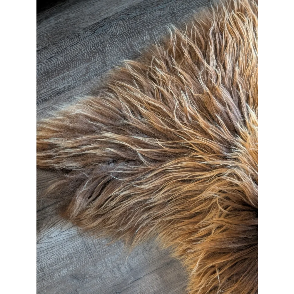 A plush 59 x 33 inch long wool icelandic sheepskin rug in warm brown and golden bronze tones
