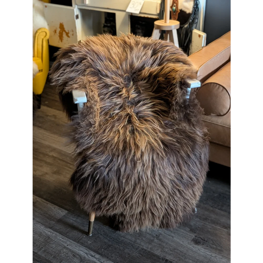 A massive 57 x 32 brown and tan plush chair with sleek metal legs made from long wool icelandic sheepskin