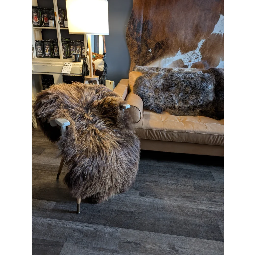 A plush brown and gray long wool icelandic sheepskin throw draped over a chair with light wooden legs