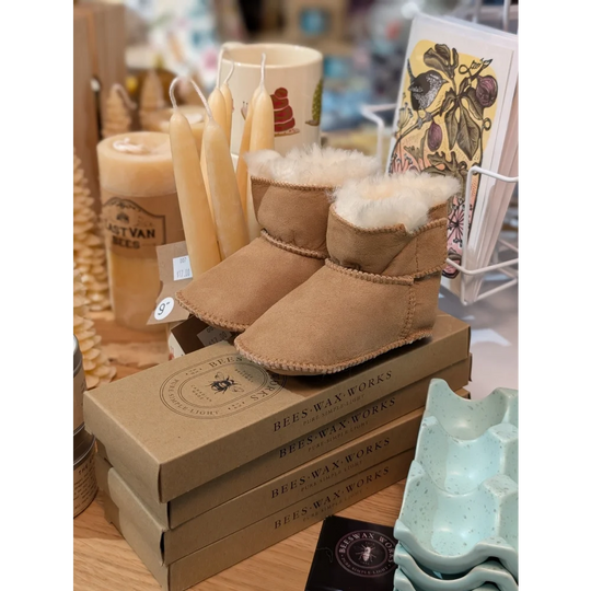 Tan sheepskin baby booties with fur lining on boxes