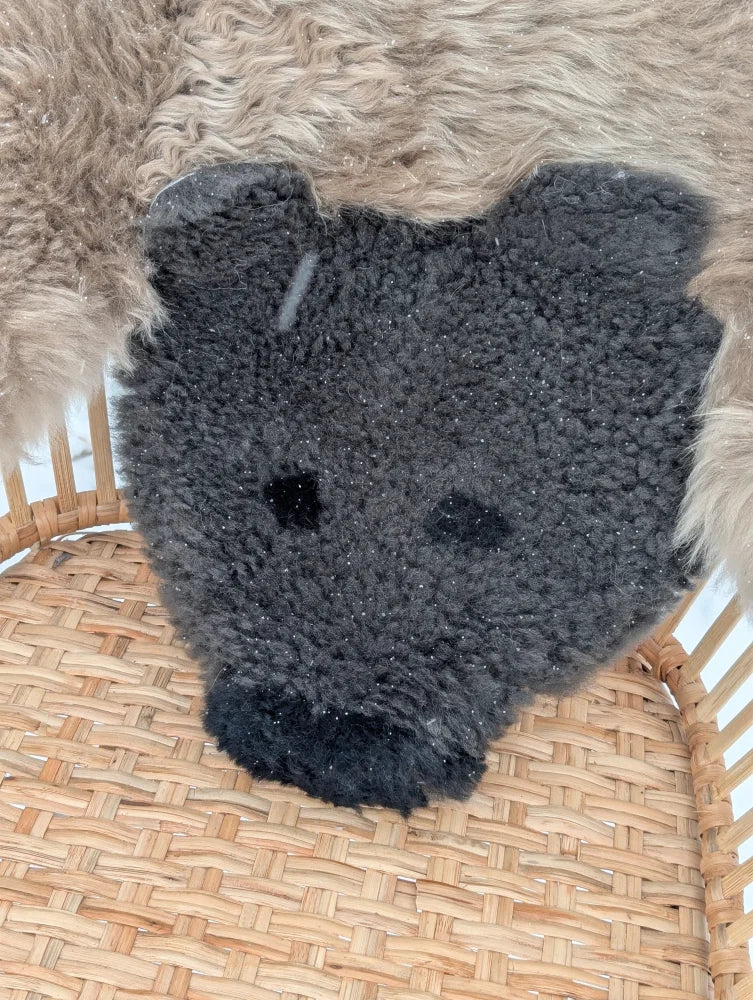 A hand made dark gray grizzly bear rug footstool made from soft merino sheepskin with embroidered black eyes