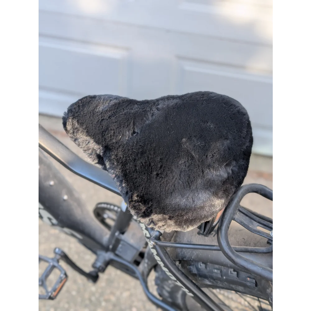 Worn black leather bike saddle with merino sheepskin cover