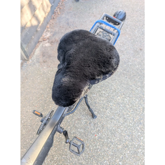 Black fuzzy merino sheepskin bicycle seat with blue accents and silver pedals