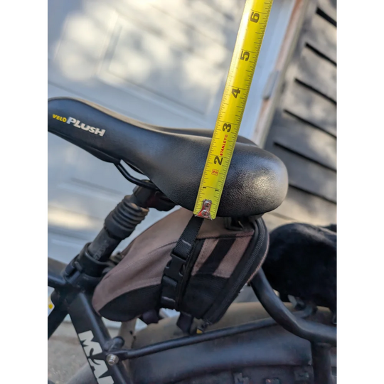 Black merino sheepskin bicycle seat with yellow tape for height adjustment