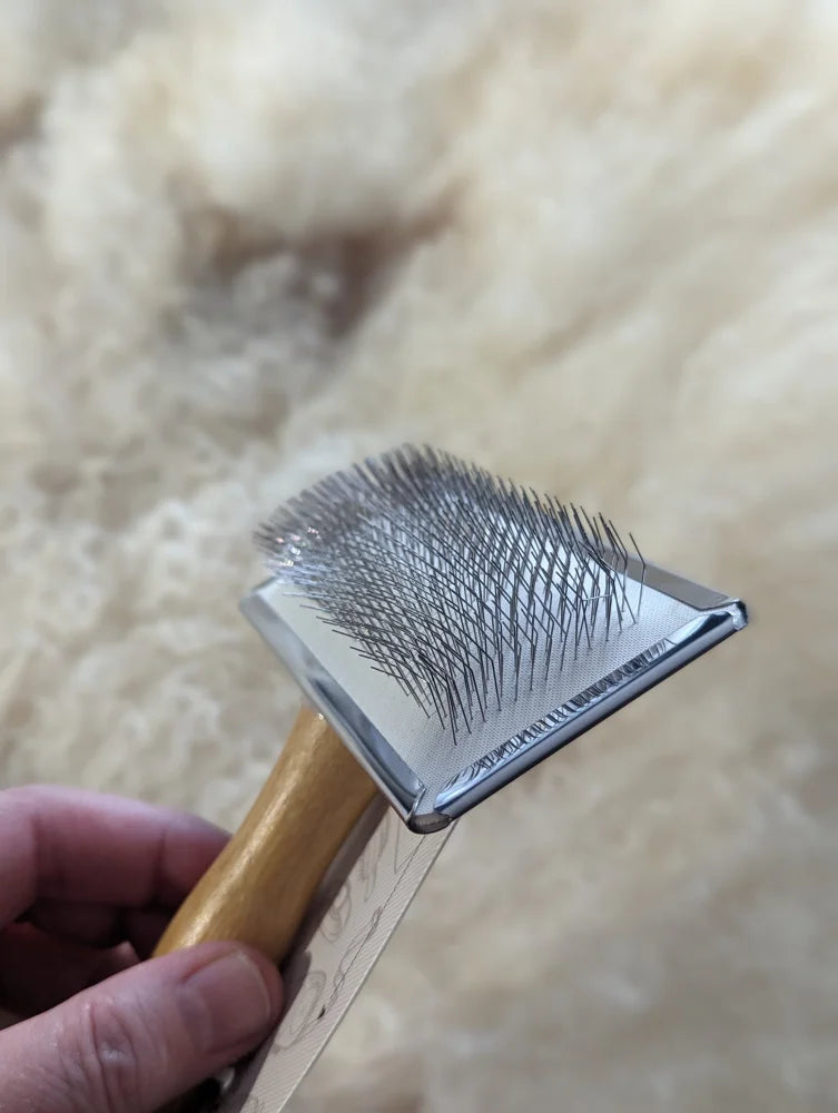 Gold and silver triangular sheepskin brush with fine teeth for pet grooming