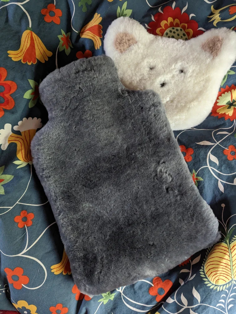 Gray fuzzy sheepskin hot water bottle with soft plush texture and rounded edges for cozy hot water comfort