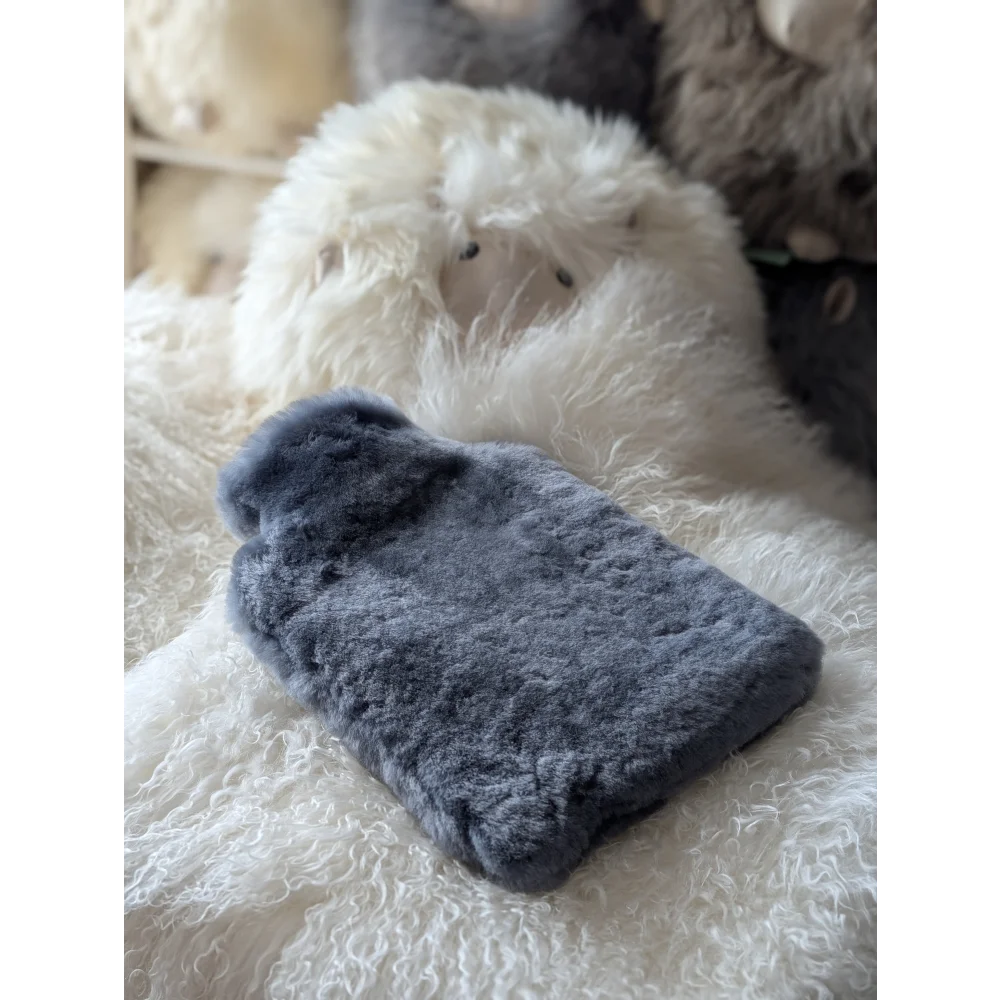 Soft sheepskin hot water bottle cover with insert on fluffy rug for chilly nights