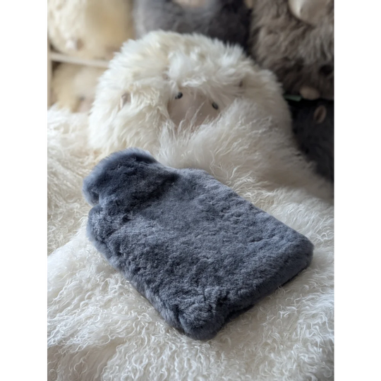 Soft sheepskin hot water bottle cover with insert on fluffy rug for chilly nights
