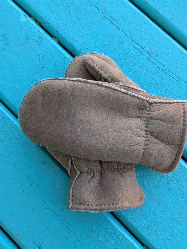 Beige sheepskin mittens with soft textured surface and white stitching perfect for cozy winter mittens or sheepskin gloves