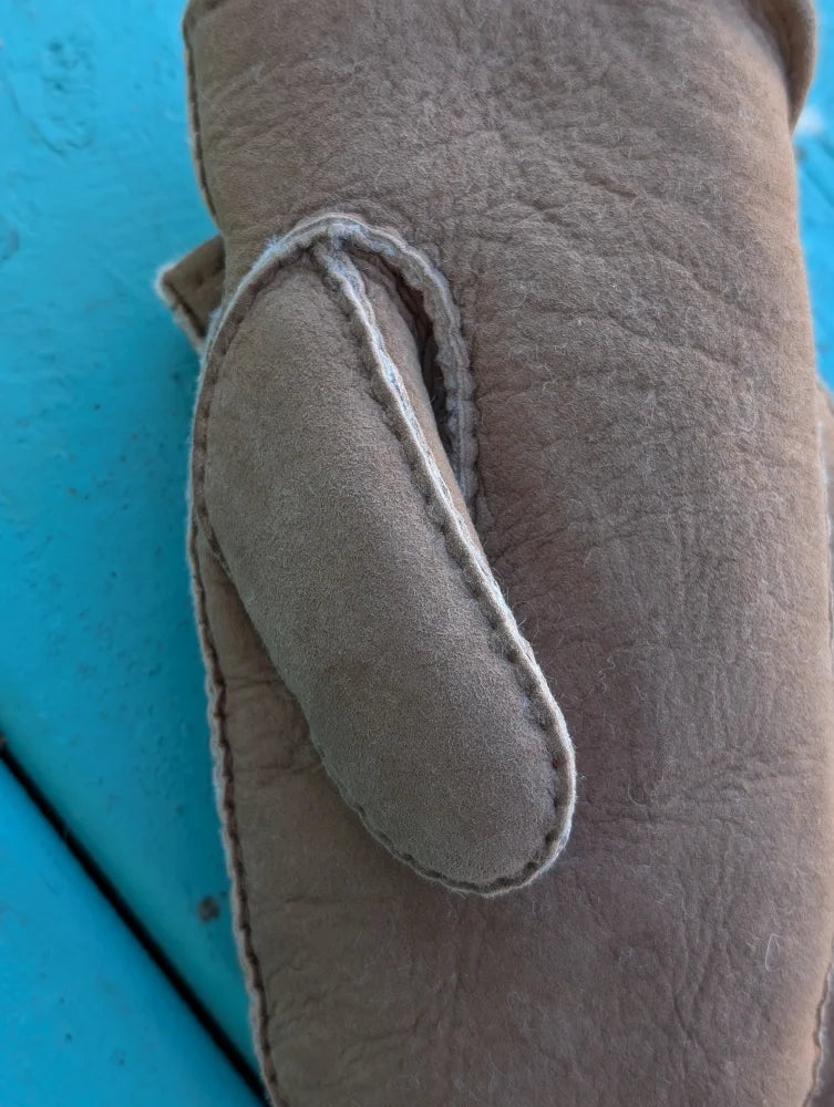 Beige sheepskin mittens showing stitched thumb loop made of soft suede for cozy winter warmth