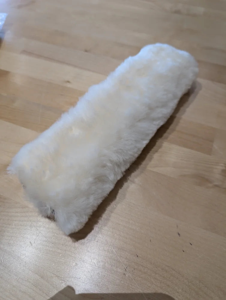 White fluffy sheepskin noseband cover on wooden floor