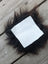 A white leather sheepskin sample square with a fluffy black faux fur border for fabric testing and design