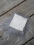 A white leather sheepskin sample square resting on soft gray fur showing texture and material quality