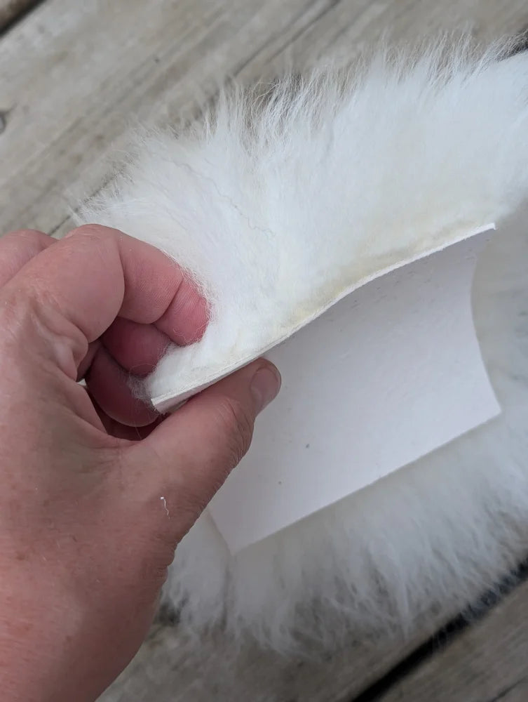 White faux fur trim with soft fluffy texture on sheepskin sample squares for cozy fabric projects