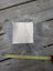 A square gray fluffy sheepskin sample with a white fabric patch centered on it