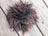 A fluffy dark brown faux fur pom pom with textured appearance shown as part of sheepskin sample squares